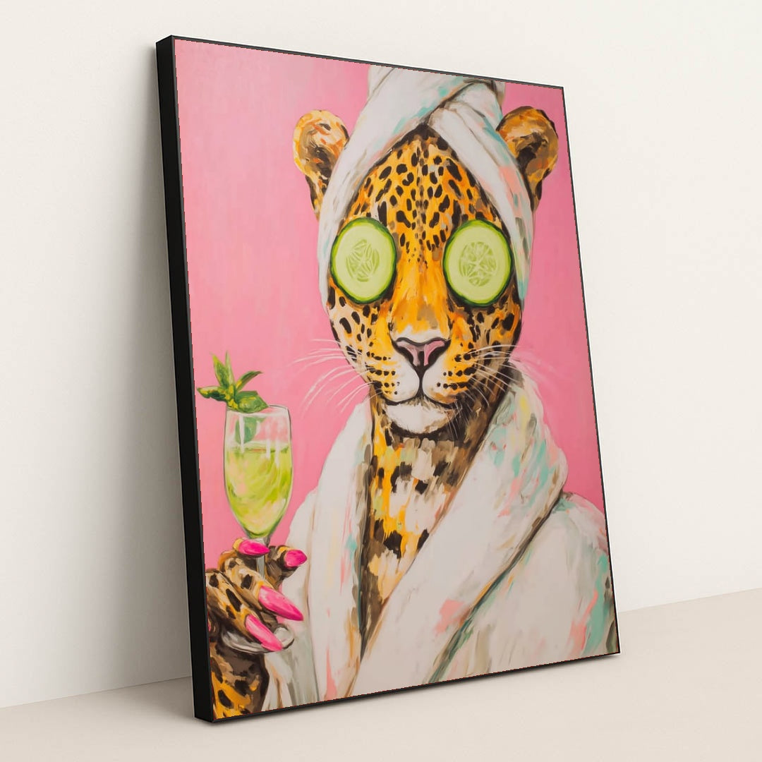 This artwork shows a playful jaguar wearing a bathrobe and towel, holding a drink, with cucumbers over its eyes, in a black frame.
