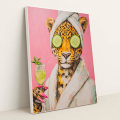 This artwork shows a playful jaguar wearing a bathrobe and towel, holding a drink, with cucumbers over its eyes, in a white frame.
