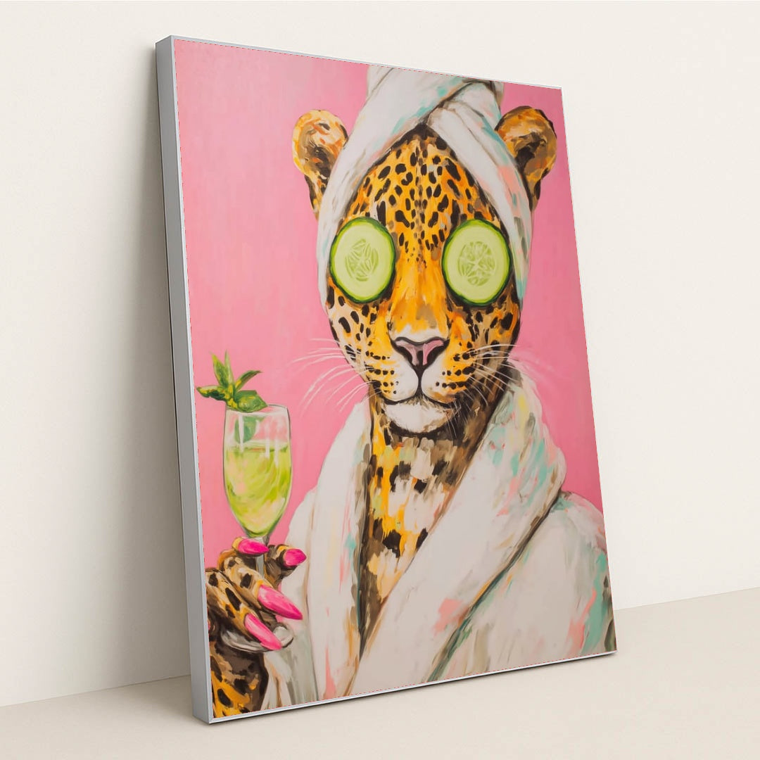 This artwork shows a playful jaguar wearing a bathrobe and towel, holding a drink, with cucumbers over its eyes, in a silver frame.