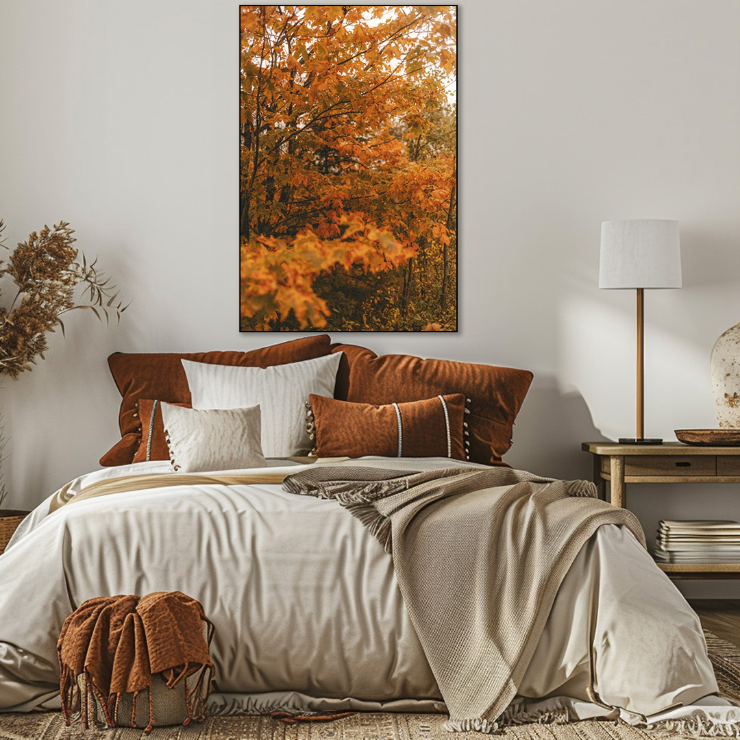 Cozy bedroom with a bed, decorative pillows, and a large framed picture of autumn foliage on the wall.