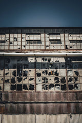 Alfo Medeiros - A captivating image of an abandoned factory showcasing broken windows and a rusty facade.