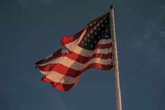Connor McManus - A vibrant American flag waves proudly on a flagpole, set against a dramatic sky.