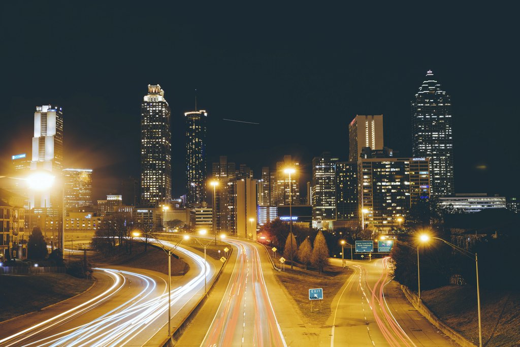 REX WAY - Stunning long exposure photo of Atlanta skyline at night with traffic light trails creating dynamic movement.