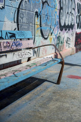 Victor Moragriega - A colorful graffiti-covered wall with a weathered bench in an urban setting. Artistic street vibe.