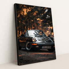This photo shows a classic black Porsche convertible parked on a forest road with golden sunlight, in a black frame.