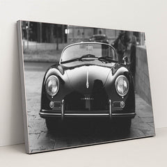This photo shows a classic black Porsche Speedster convertible parked on a city street in black and white, in a silver frame.