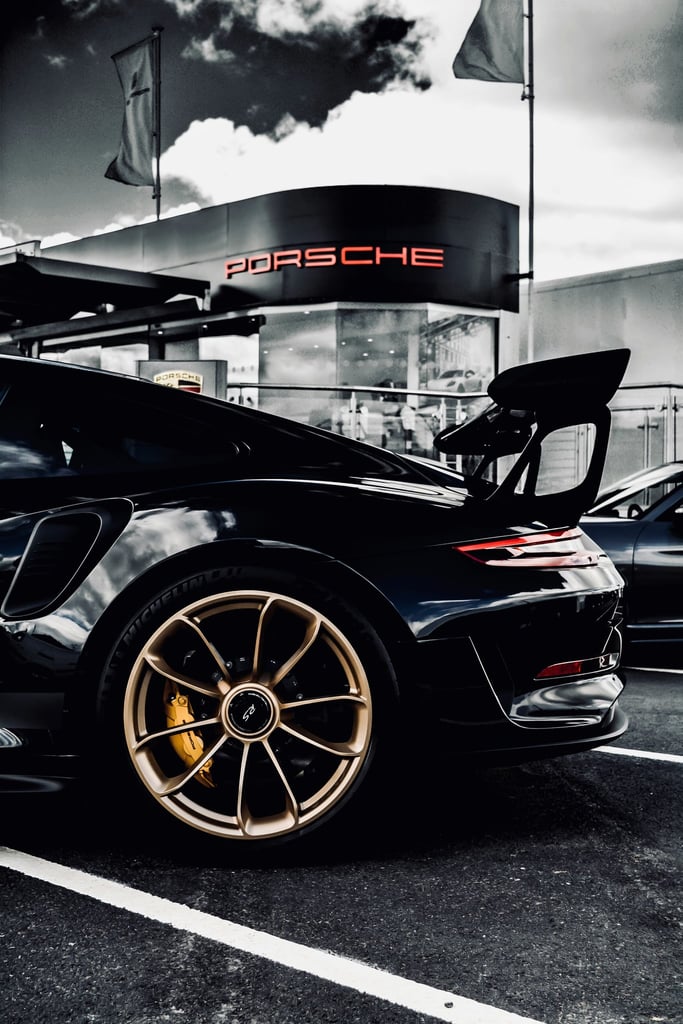 GT2 Outside Porsche parked in front of dealership, showcasing its sleek design and gold wheels, ideal for car wall art.