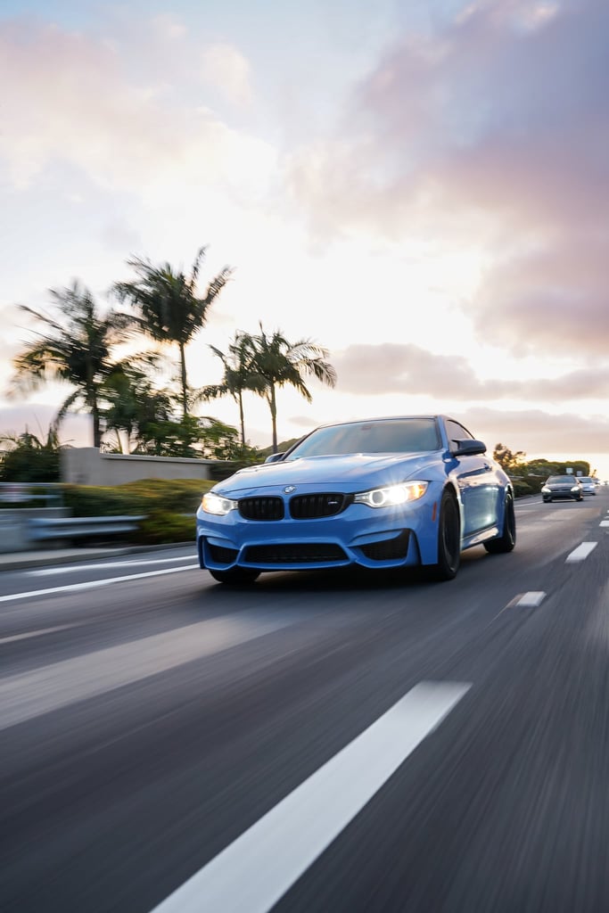 BMW M4 in Motion driving on a vibrant road, palm trees in the background, perfect car wall art for any space.
