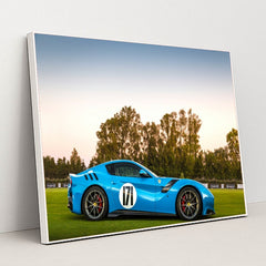 This photo shows a blue Ferrari sports car with racing stripes and the number 171 parked on grass at sunset, in a white frame.