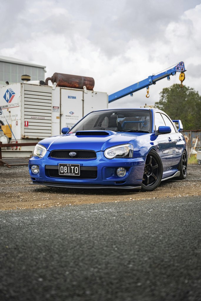 Blue Subaru WRX STI in Industrial Setting parked against a gritty backdrop, showcasing dynamic design as car wall art.