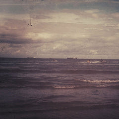 Suzy Hazelwood - Rustic ocean scene with small waves and distant ships under a cloudy sky, exuding a vintage feel.