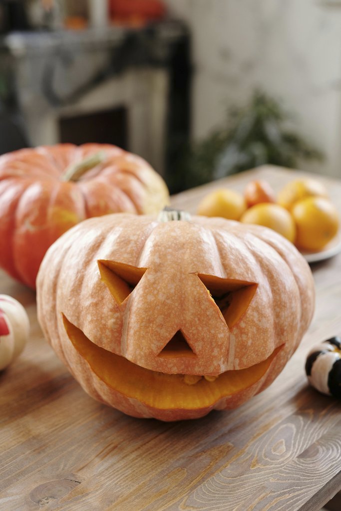 Daisy Anderson - Carved pumpkin with festive decor indoors, perfect for Halloween season.