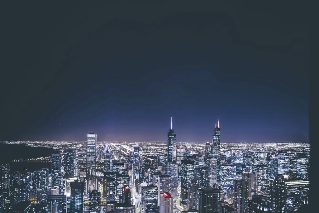 Guillermo Arroyo - Stunning aerial view of a city skyline illuminated at night with skyscrapers and vivid lights.