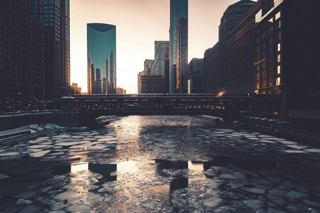 Max Bender - A stunning view of Chicago's frozen river surrounded by modern skyscrapers at twilight.