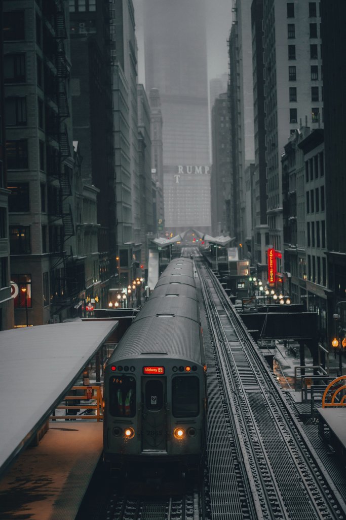 Praneeth Koduru - A train navigates through a foggy city with towering skyscrapers and urban structures, creating a moody atmosphere.