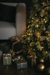 Lisett Kruusim - Cozy Christmas scene with a beautifully decorated tree and elegant wrapped presents around an armchair.