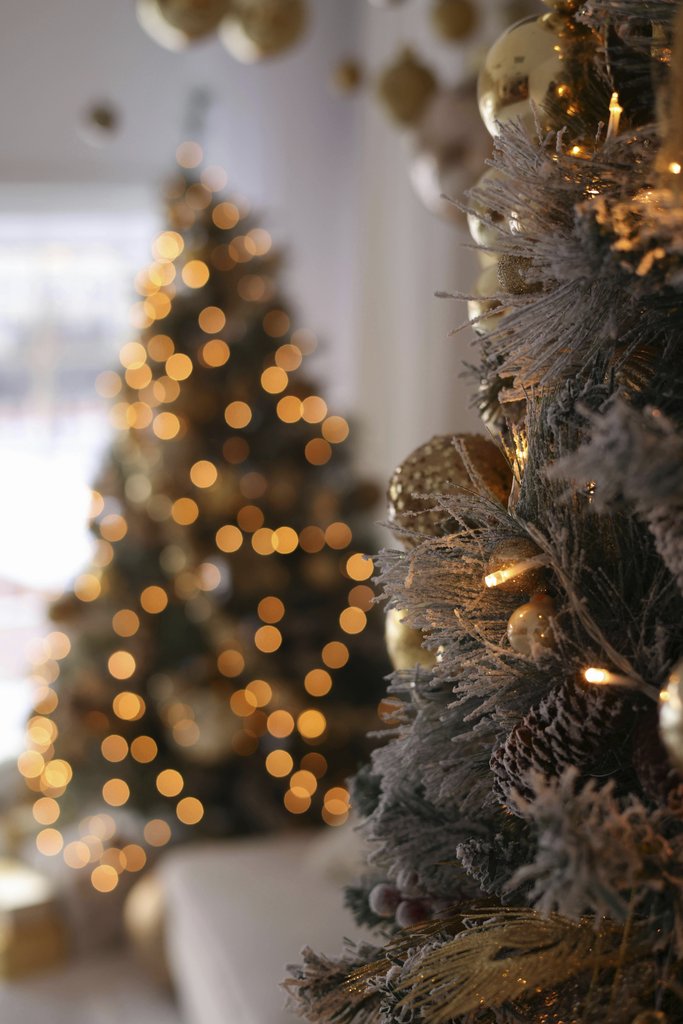 Valeria Boltneva - Beautiful Christmas tree with golden ornaments and bokeh lights creating a festive ambiance indoors.