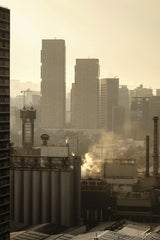 Rulo Mora - Cityscape view of Ciudad de México with high-rise buildings and industrial elements at sunset.