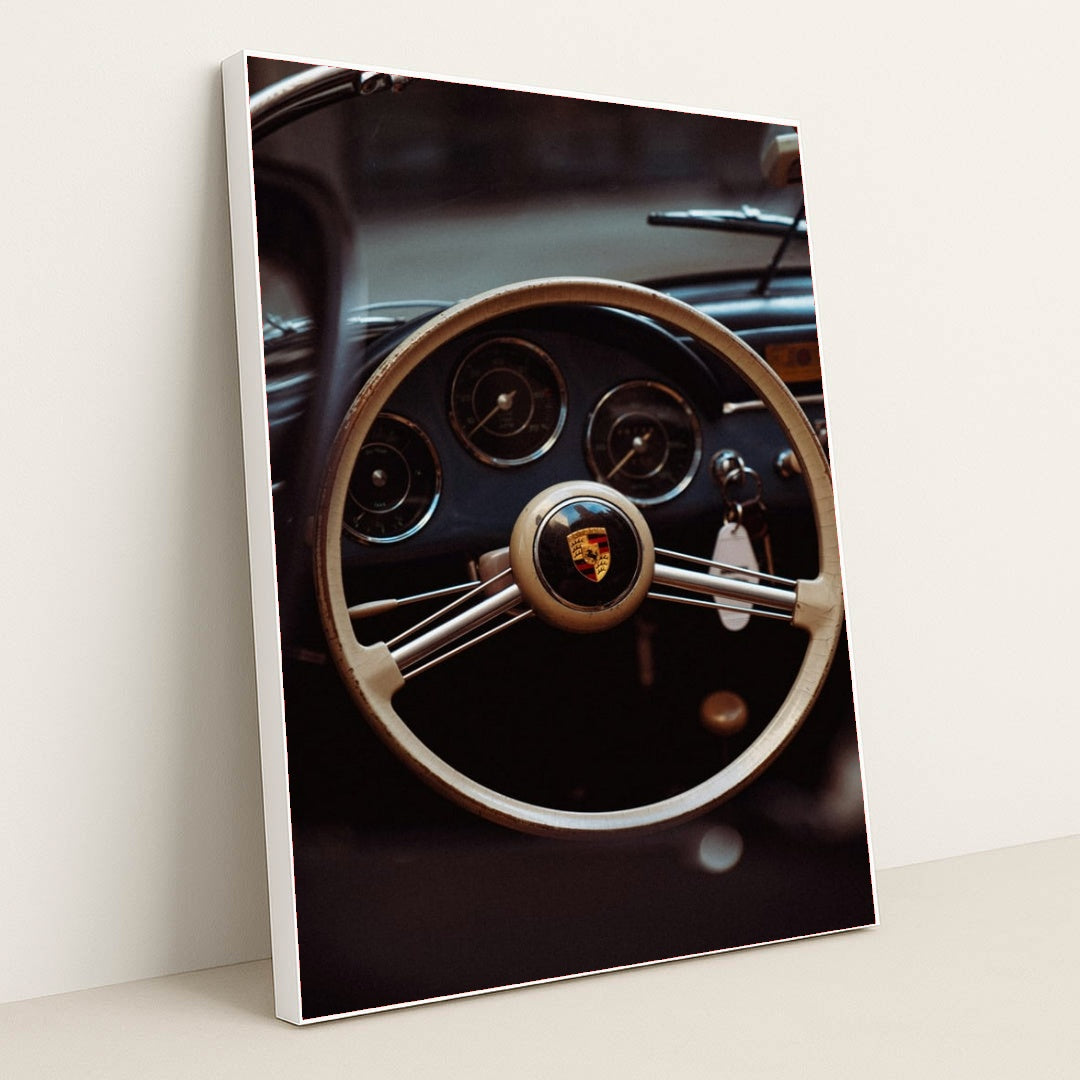 This photo shows the vintage steering wheel and gauges of a classic Porsche car, in a white frame.
