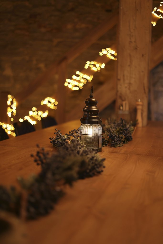 Valeria Boltneva - Cozy indoor space with warm lighting, lantern, and rustic wooden decor on a table.