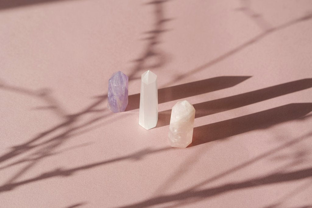 Mikhail Nilov - An artistic arrangement of crystals casting shadows on a soft pink background, creating a serene still life composition.