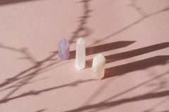 Mikhail Nilov - An artistic arrangement of crystals casting shadows on a soft pink background, creating a serene still life composition.