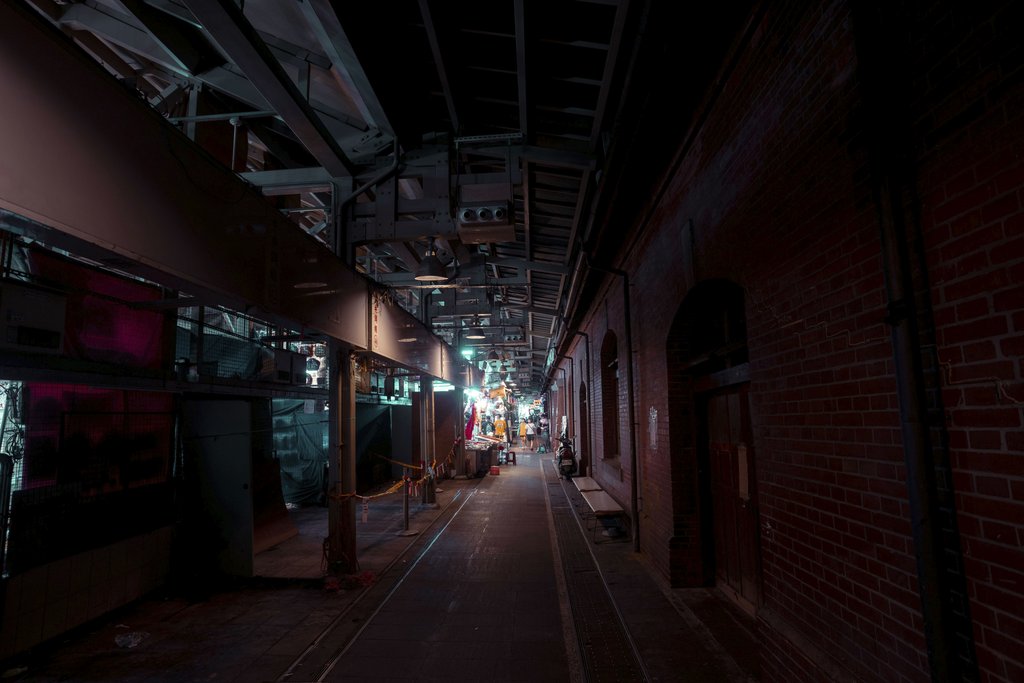 Jimmy Liao - Dark urban alley with industrial architecture and neon lighting creating a moody atmosphere.