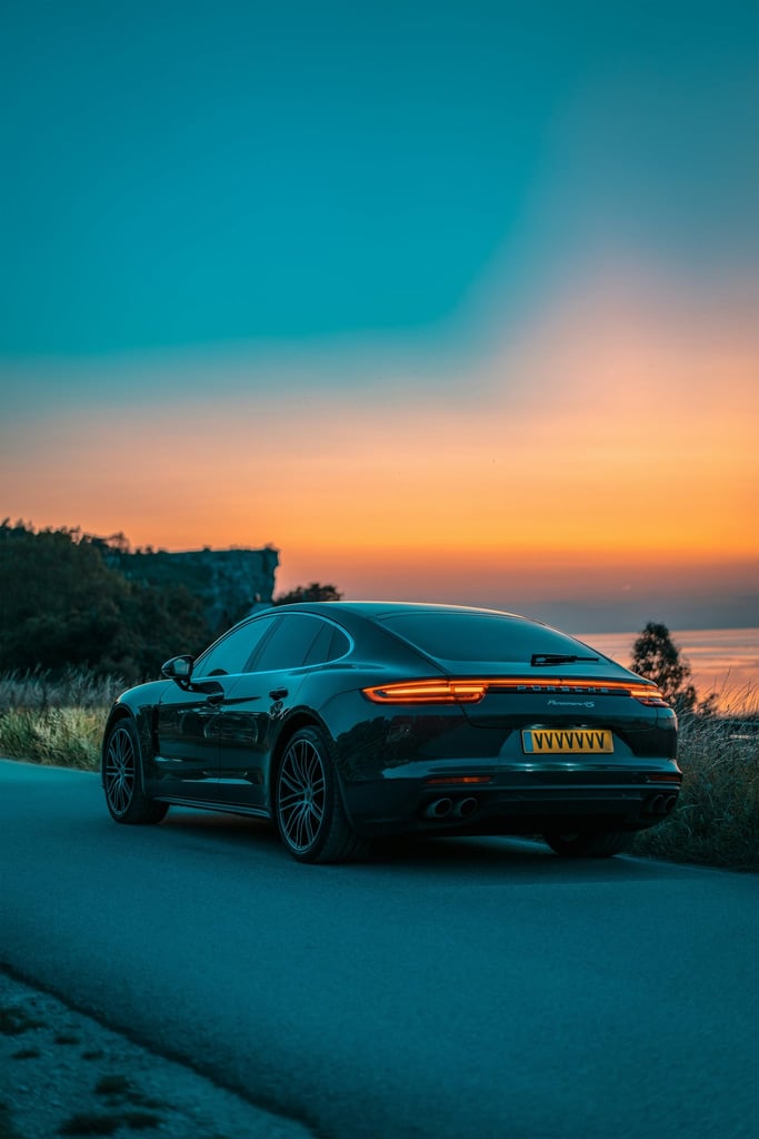 Porsche Panamera at Dusk on the Coast, sleek car silhouette against a vibrant sunset and ocean view, perfect car wall art.