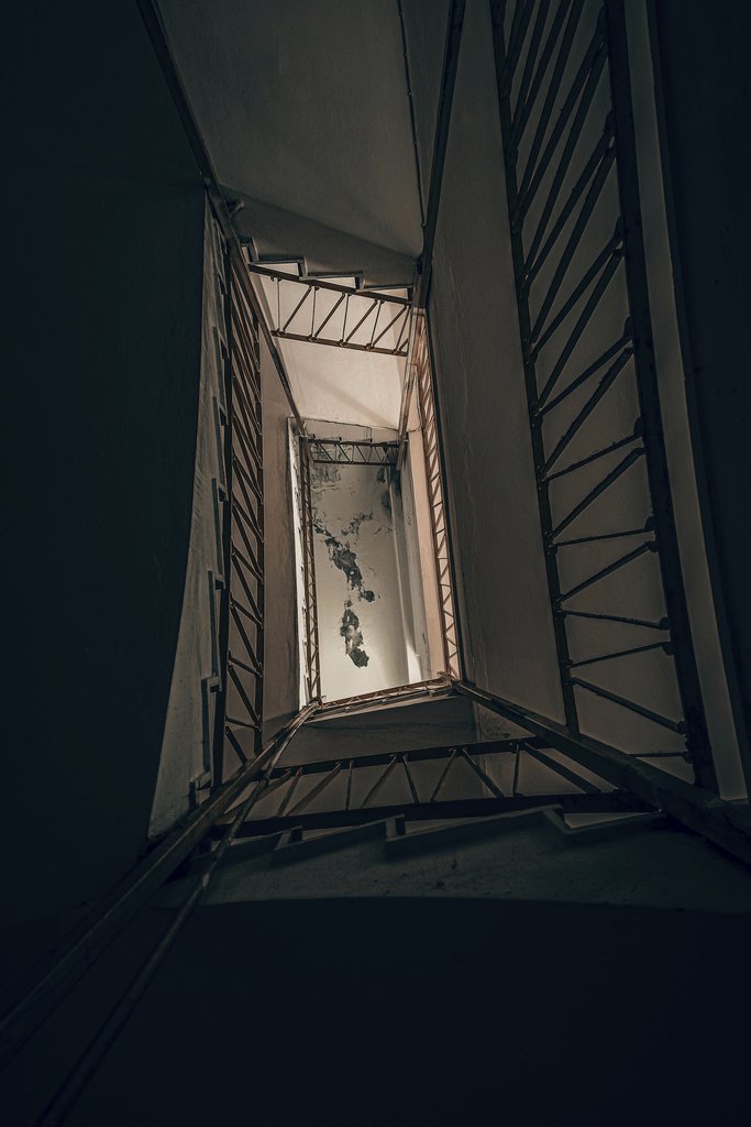 Atahan Demir - A moody and abstract perspective of a deteriorating staircase with iron railings.
