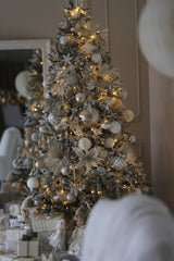 Valeria Boltneva - Beautifully decorated Christmas tree with silver and white ornaments, softly lit indoors for a festive ambiance.