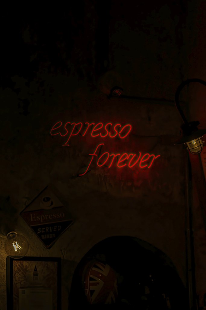 IDRISS BELHAMADIA - A dark moody café featuring a vibrant red 'espresso forever' neon sign.