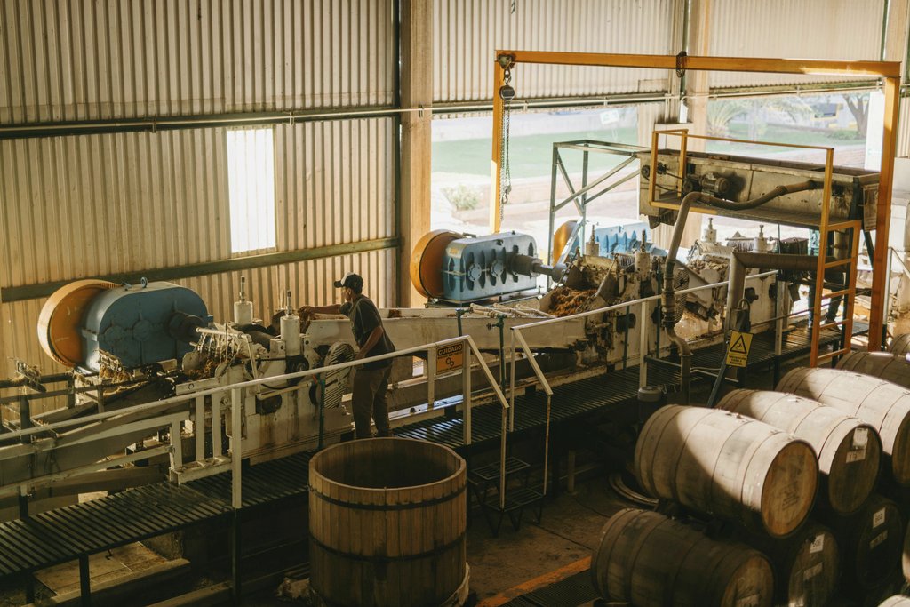 Los Muertos Crew - Interior view of a tequila factory with machinery and barrels in Mexico.