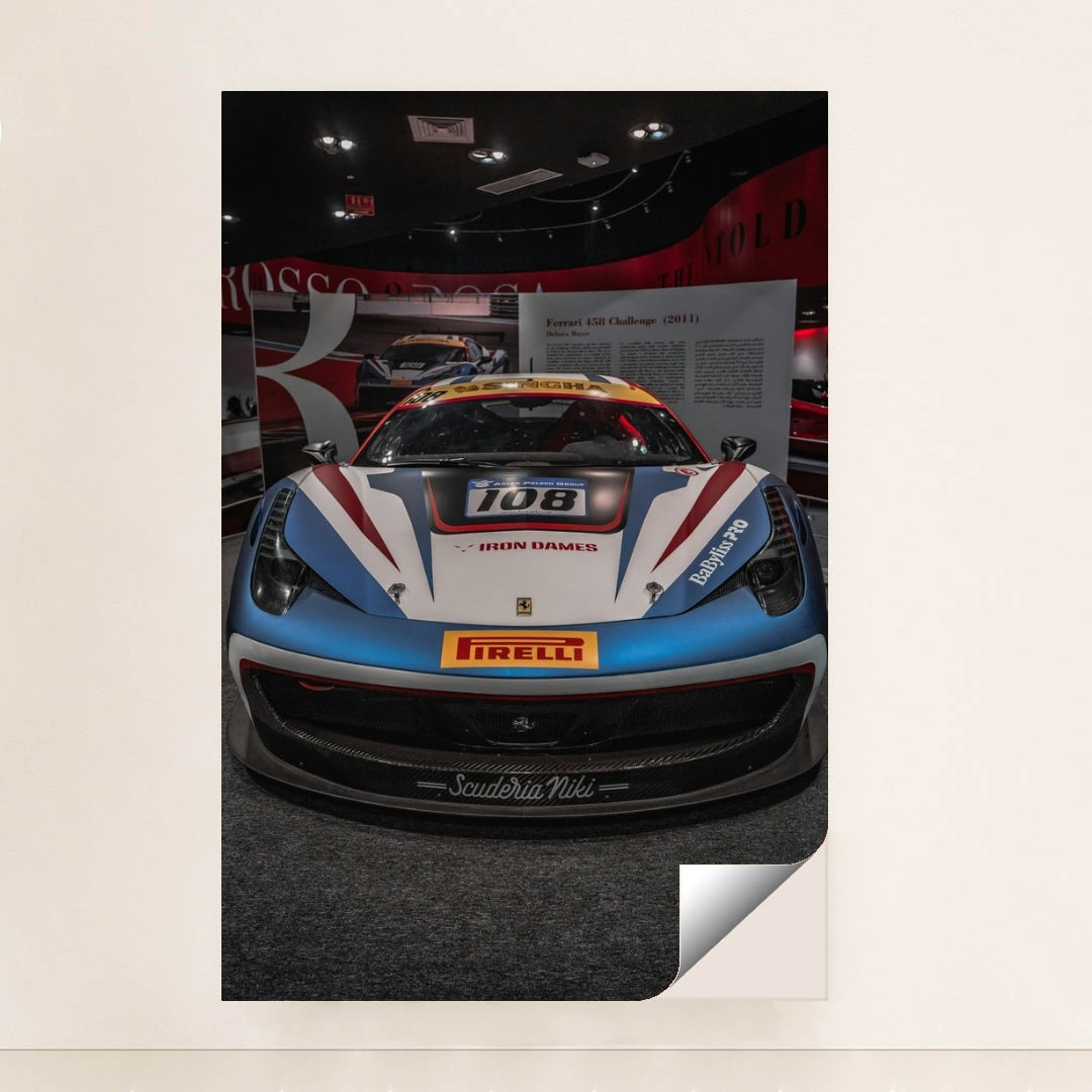 This photo shows the front view of a Ferrari 458 Challenge race car with Iron Dames and Pirelli branding in a museum, unframed.