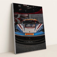 This photo shows the front view of a Ferrari 458 Challenge race car with Iron Dames and Pirelli branding in a museum, in a silver frame.