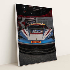 This photo shows the front view of a Ferrari 458 Challenge race car with Iron Dames and Pirelli branding in a museum, in a white frame.