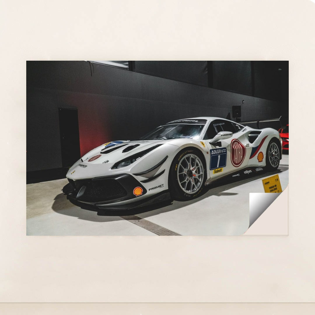 This photo shows a white Ferrari 488 Challenge Evo race car with sponsor decals displayed indoors, unframed style.