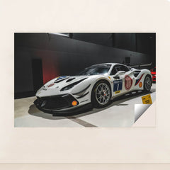 This photo shows a white Ferrari 488 Challenge Evo race car with sponsor decals displayed indoors, unframed style.