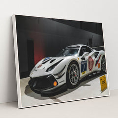 This photo shows a white Ferrari 488 Challenge Evo race car with sponsor decals displayed indoors, in a white frame.
