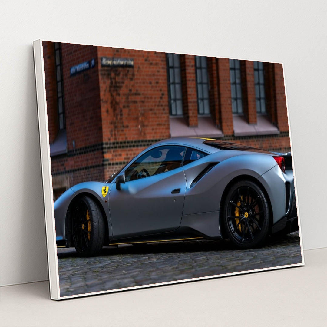 This photo shows a matte grey Ferrari 488 Pista with black wheels and yellow calipers parked by a brick building, in a white frame.