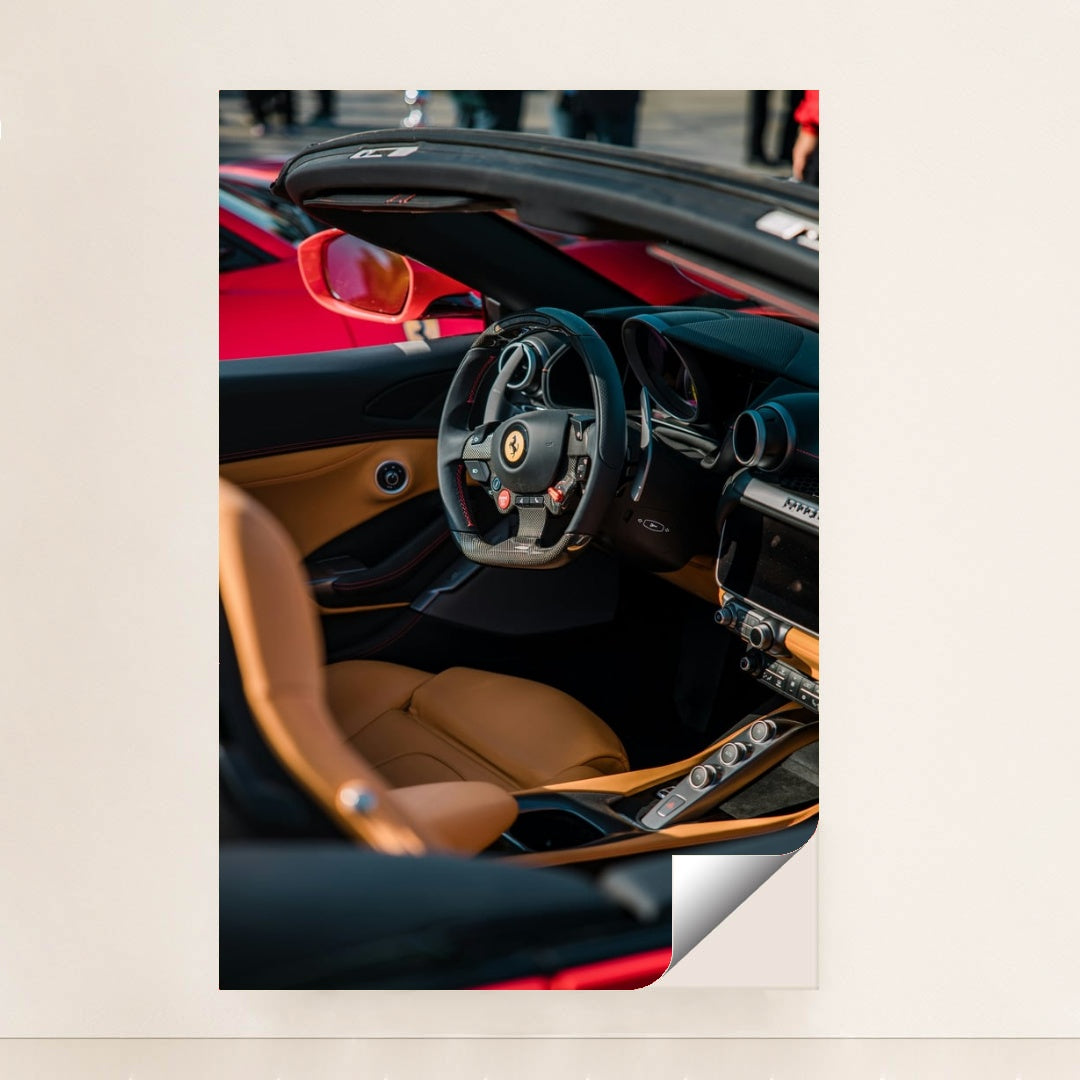This photo shows the interior of a Ferrari convertible with tan leather seats and a carbon fiber steering wheel, minimalist unframed style.