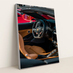 This photo shows the interior of a Ferrari convertible with tan leather seats and a carbon fiber steering wheel, in a silver frame.