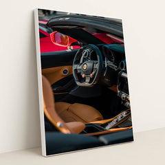 This photo shows the interior of a Ferrari convertible with tan leather seats and a carbon fiber steering wheel, in a white frame.