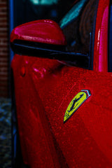 Close-up of a Ferrari in the Rain highlighting its red paint and yellow shield, perfect for car wall art.