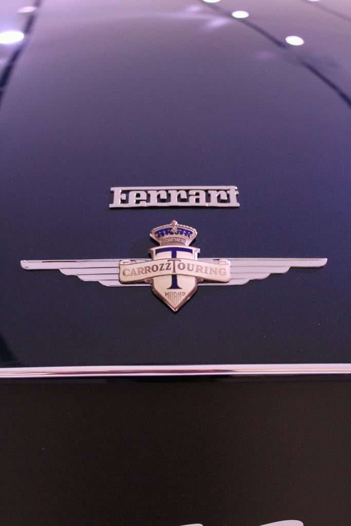 Close-up of Ferrari's Carrozz Touring Badge on sleek black surface, perfect for car wall art.