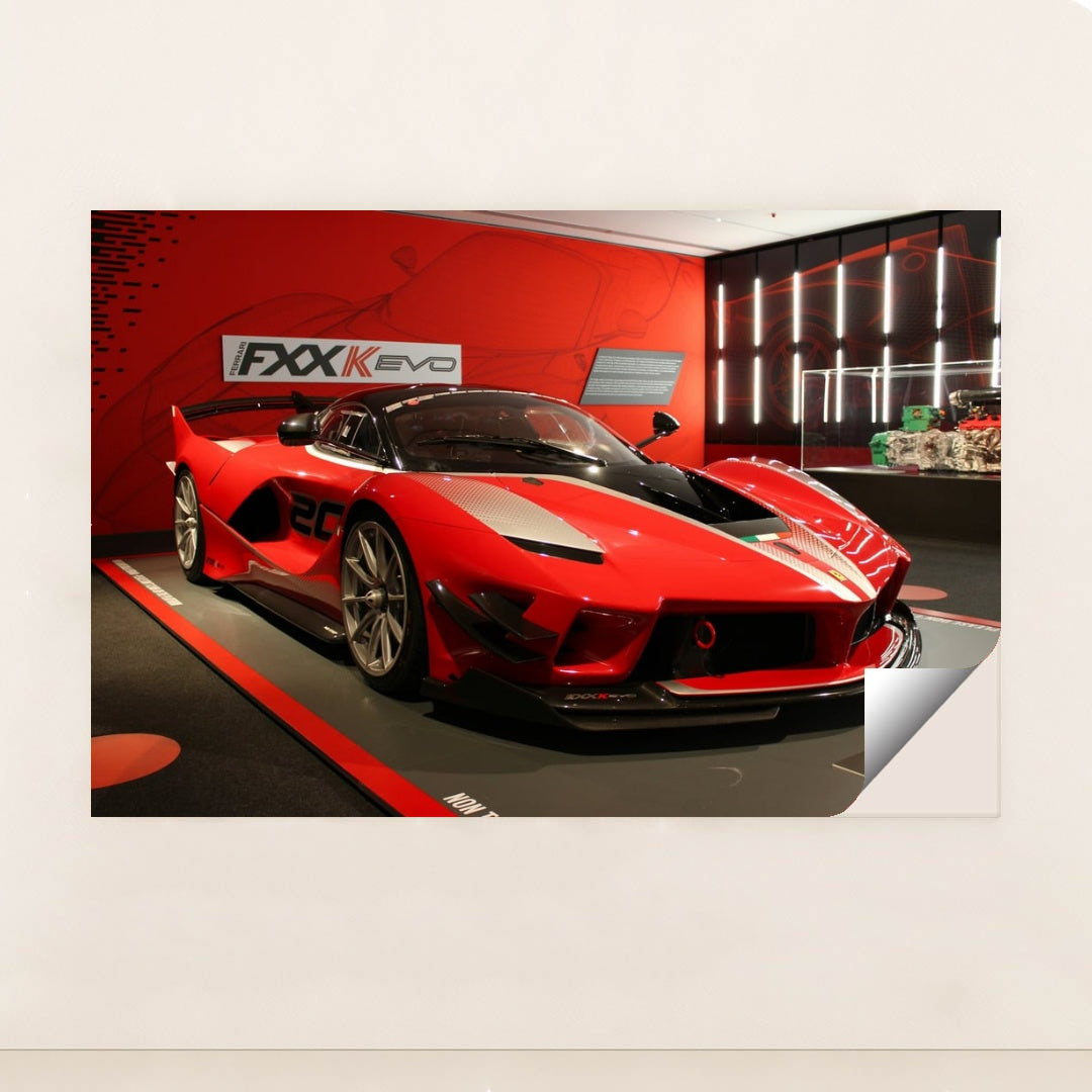 This photo shows a red Ferrari FXX-K Evo race car on display in a museum with red walls, unframed style.