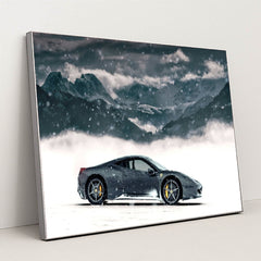 This photo shows a black Ferrari coupe parked in snow with snowy mountains in the background, in a silver frame.
