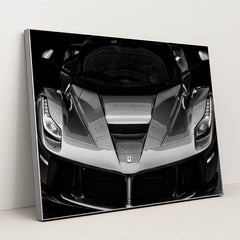 This photo shows the front view of a Ferrari hypercar in dramatic black and white, in a silver frame.