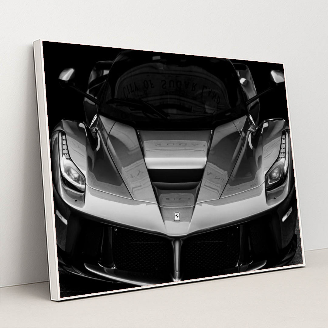 This photo shows the front view of a Ferrari hypercar in dramatic black and white, in a white frame.