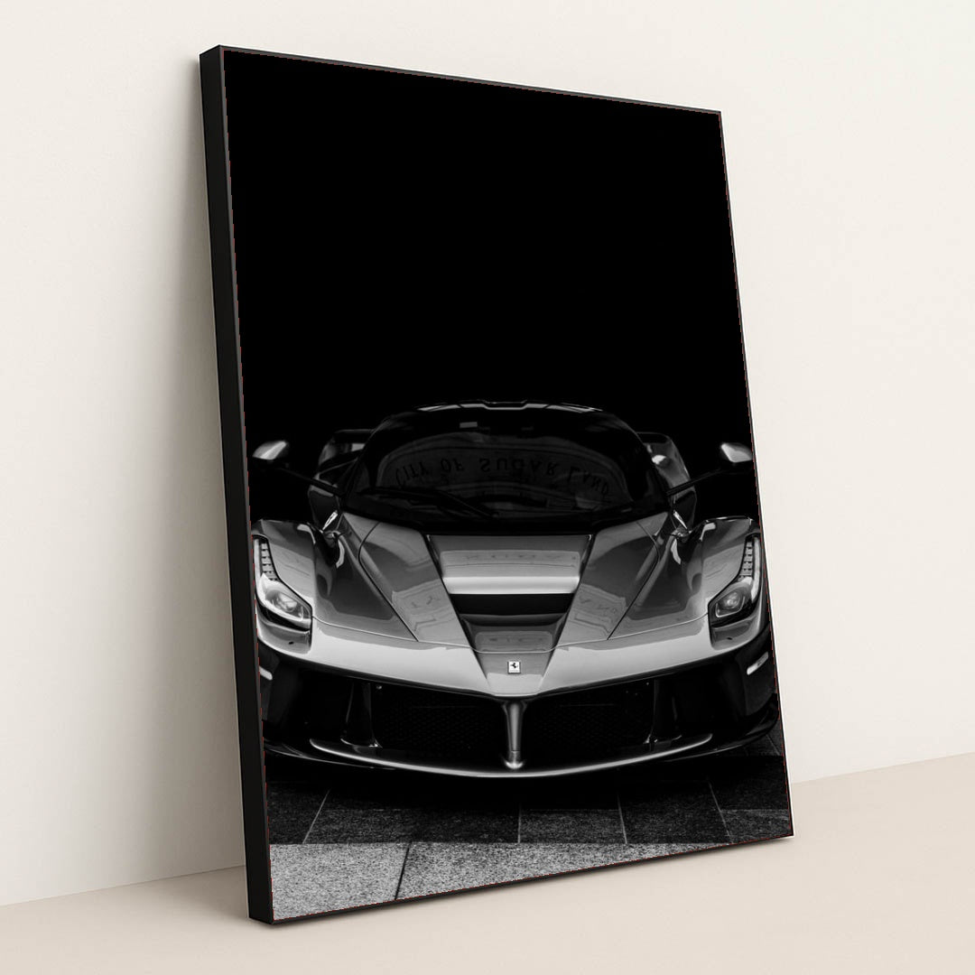 This photo shows a black and white front view of a Ferrari LaFerrari against a dark background, in a black frame.