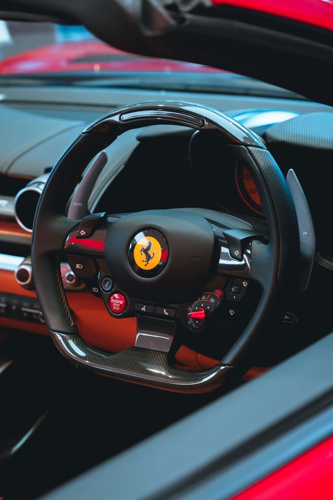 Close-up of a Ferrari Steering Wheel showcasing black leather, carbon fiber, and iconic Ferrari badge for car wall art.